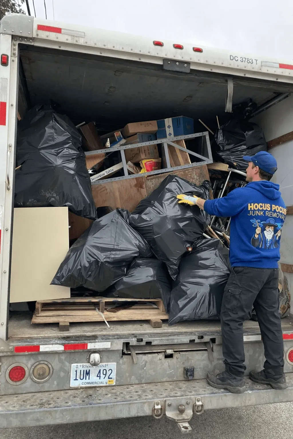 Hocus Pocus Junk Removal crew loading bagged junk into a truck